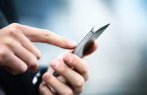 close up of a person holding a cell phone using their index finger on the screen
