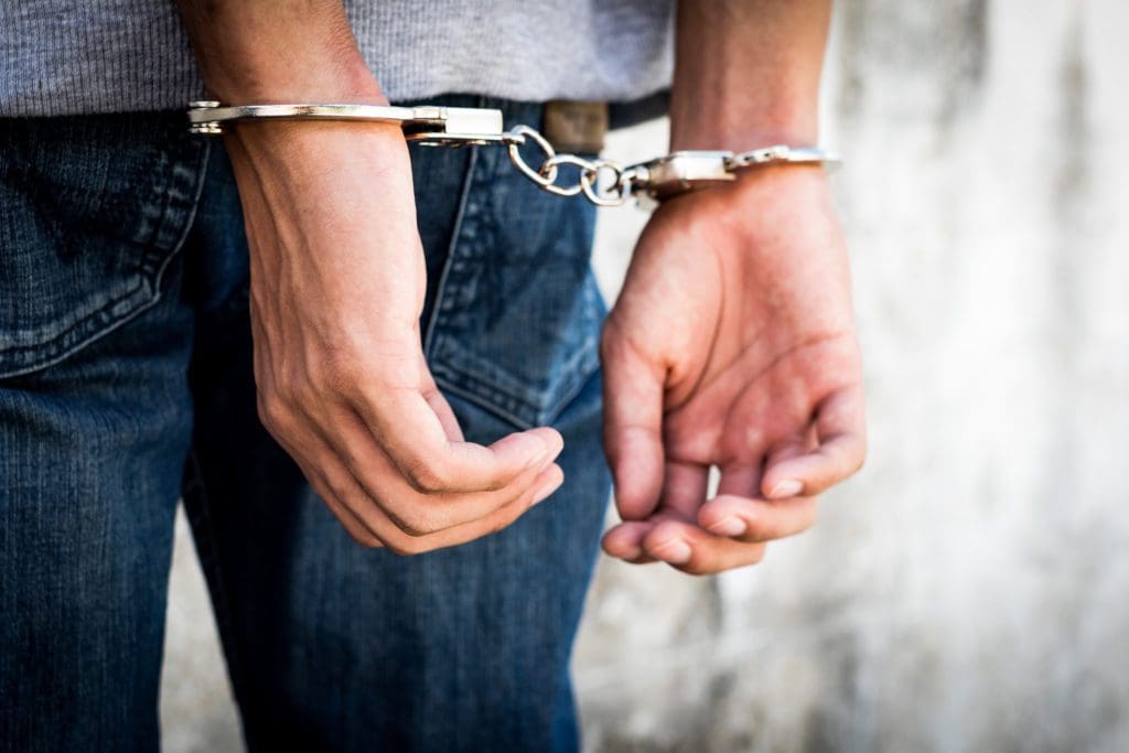 Close of up of someone with their hands cuffed behind their back.