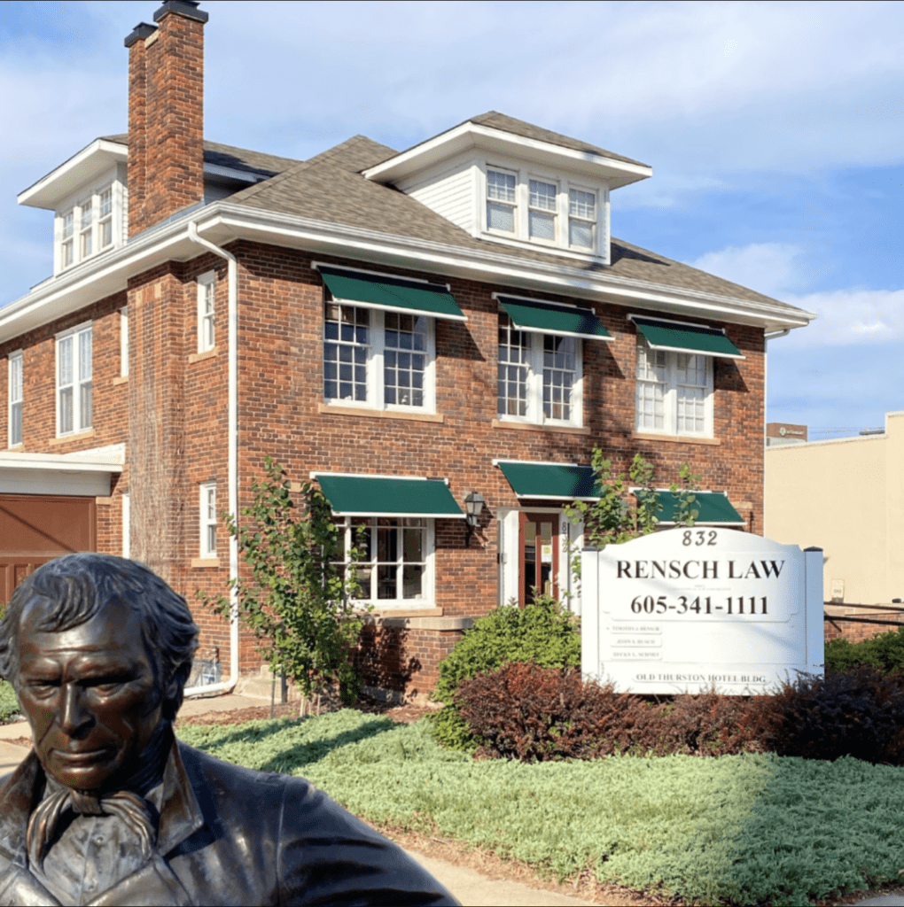 historic Square brick building with green shutters and a sign for rensch law office